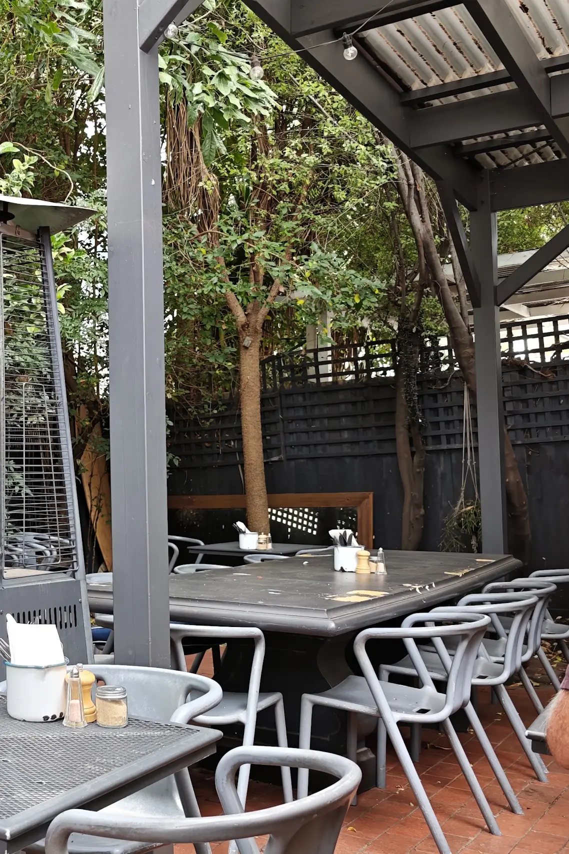 Tables under the new pergola, with a patio heater among the plants