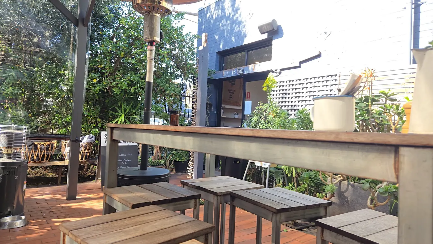 Timber tables under the pergola in the morning sun