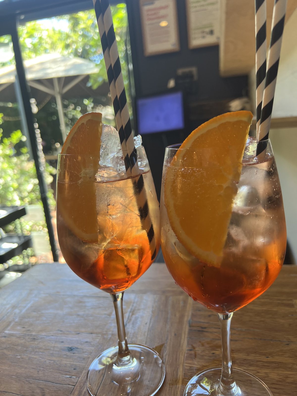 Two Aperol spritzes on a courtyard table